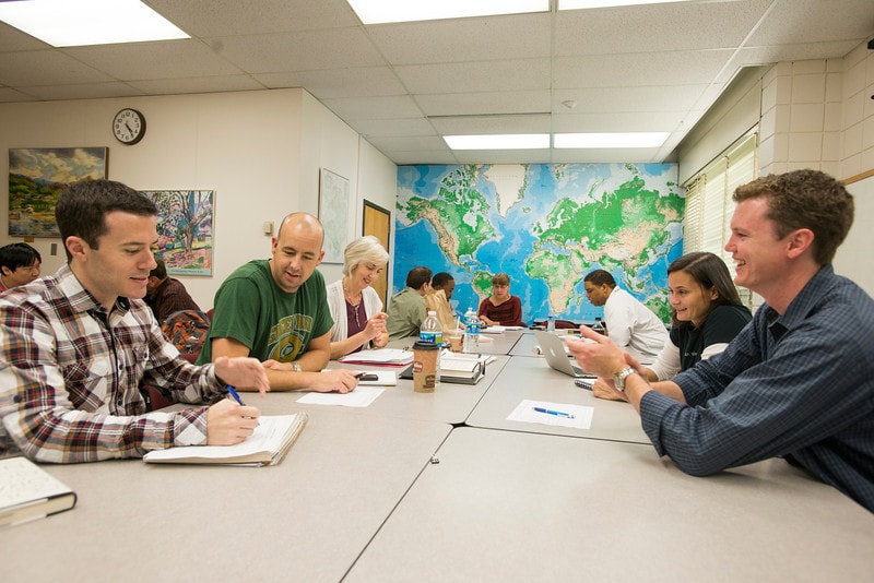 photo of a student discussion with a map in the background