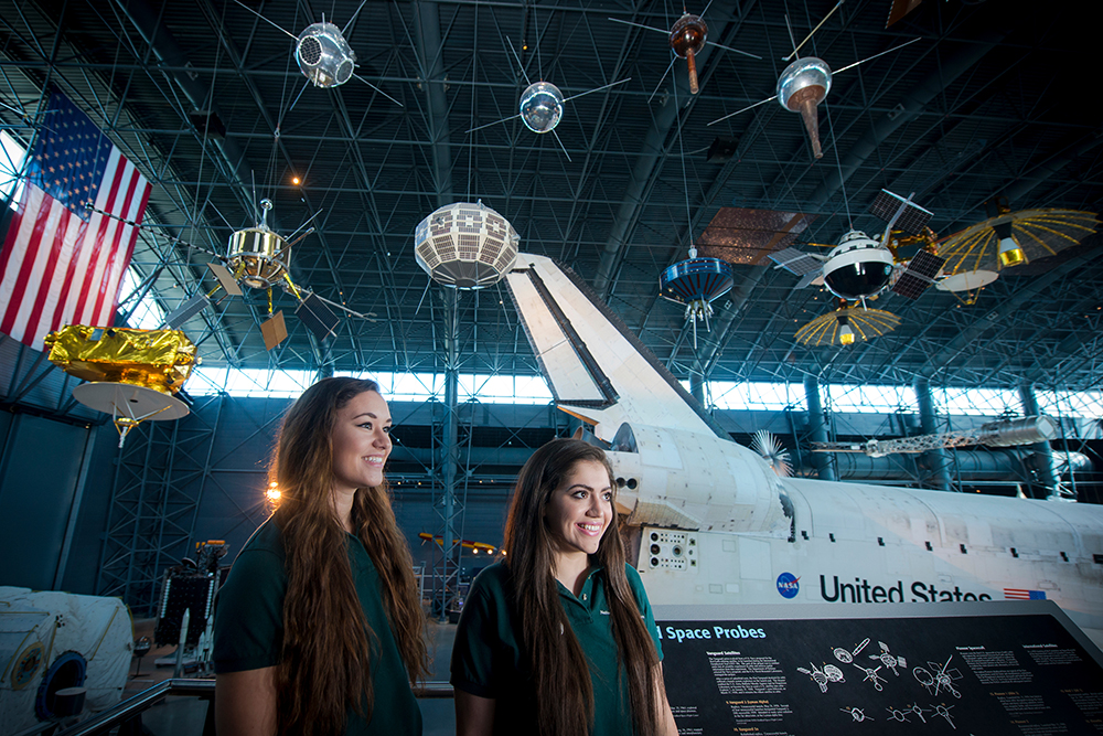 Honors College students Suzy Hewitt (on left) and Roxana Kazemi work as interns in the Explainers Program at the Steven F. Udvar-Hazy Center, National Air and Space Museum. Photo by Evan Cantwell/Creative Services/George Mason University