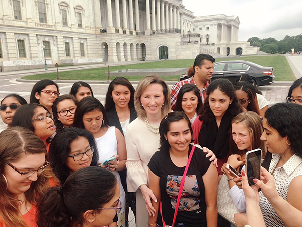 Former U.S. Representative Barbara Comstock is surrounded by young women in front of the U.S. Capitol building in Washington, D.C.