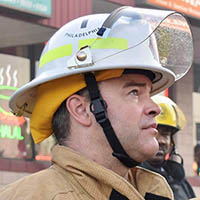 A man in a fireman’s helmet gazes to the right.