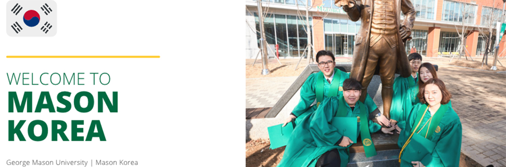 A group of 4 Mason Korea students sit near the George Mason statue on the Fairfax Campus while wearing green caps and gowns.