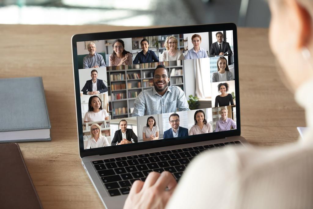 Someone takes a video call on a laptop filled with the grid of different participants.