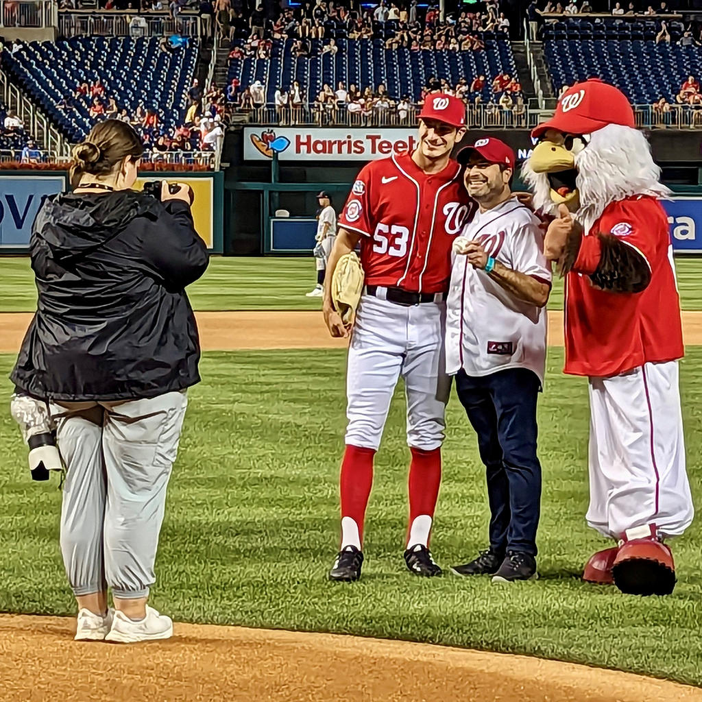 Schar School graduate and adjunct professor Craig Fifer is flanked by National’s pitcher Joe La Sorsa (left) and mascot Screech (right) after delivering his ceremonial first-pitch. Photo by Alex Perry.
