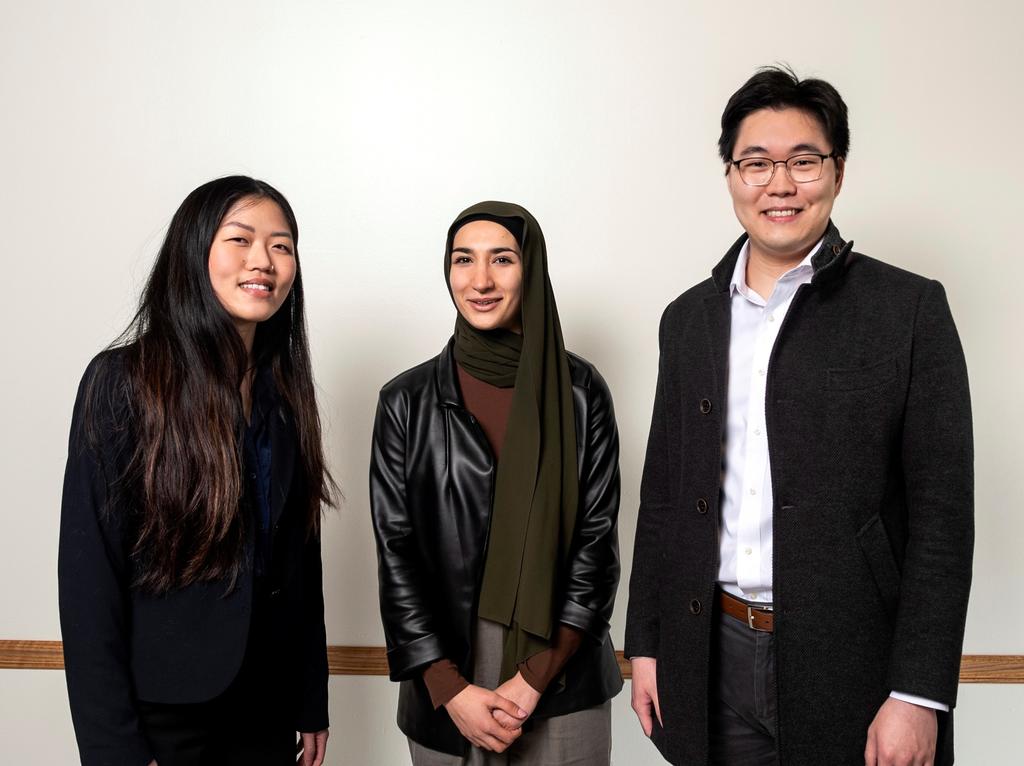 Three Mason students in professional clothing looking at the camera and smiling. 